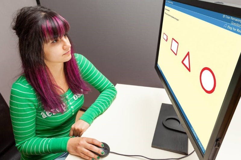 a young lady sits down at a computer to take the UK driving theory test