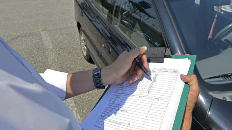 A photograph of a driving examiner writing on a marksheet