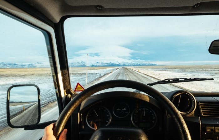 Photograph of a driver driving a car on a snowy road