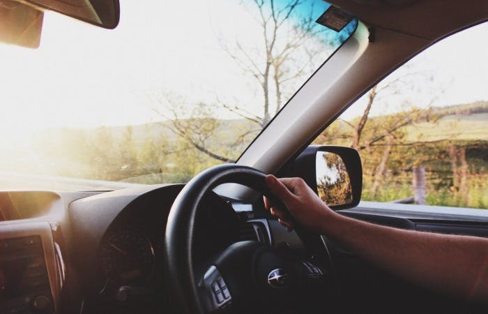 Photograph of a person's hand holding a car's steering wheel