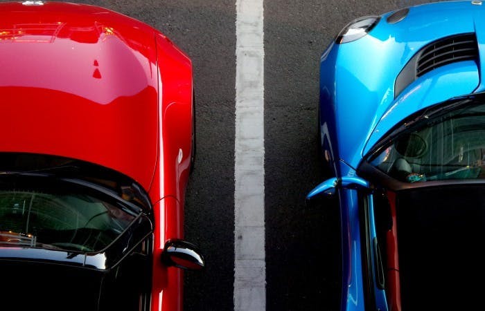 A birds eye view photograph of two cars parked in parking bays