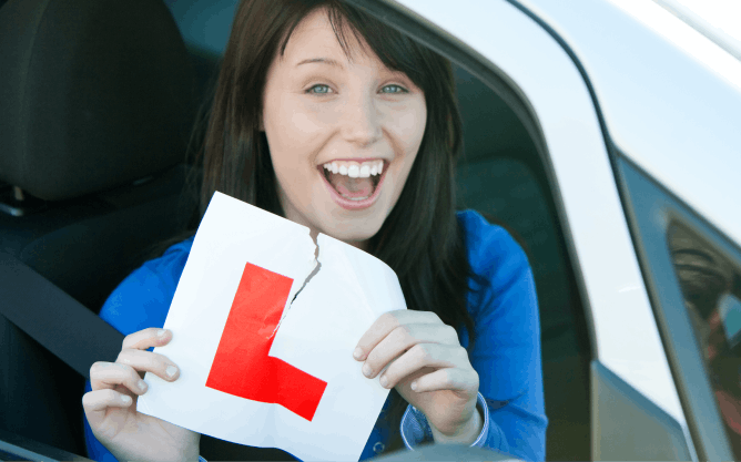 A happy woman tearing up her L plate after passing her driving test