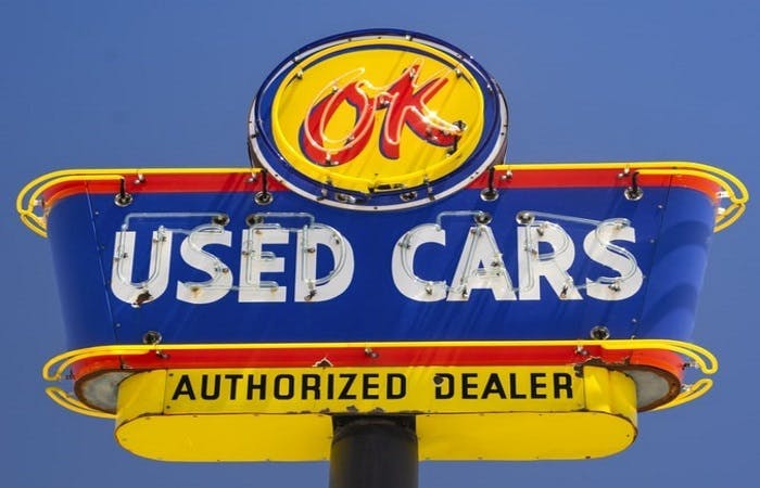 A blue and yellow used car sign