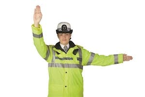 Police officer directing traffic from in front and behind her to stop using a hand signal