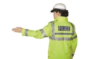 Police officer directing traffic behind her to stop using a hand signal
