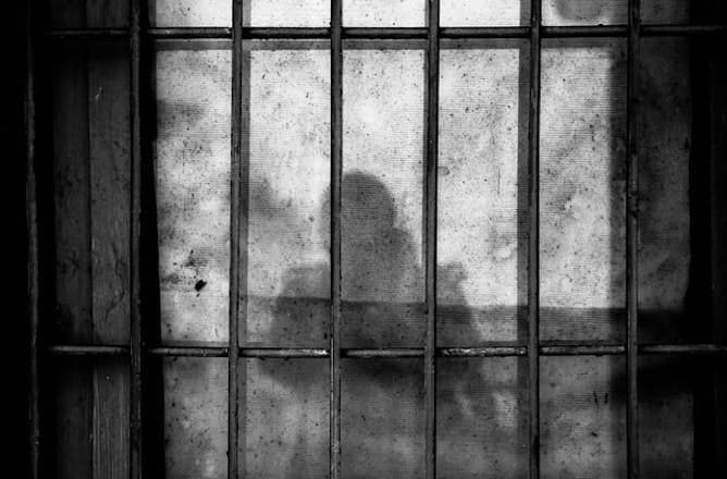 silhouette of person behind bars 