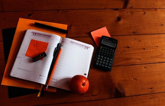 A calculator organiser and orange on a table