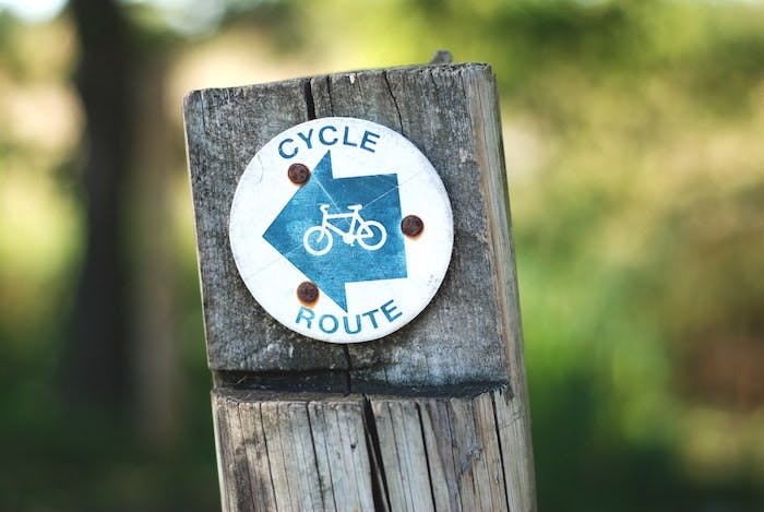 Photograph of a wooden signpost. The sign reads 'Cycle Route'.