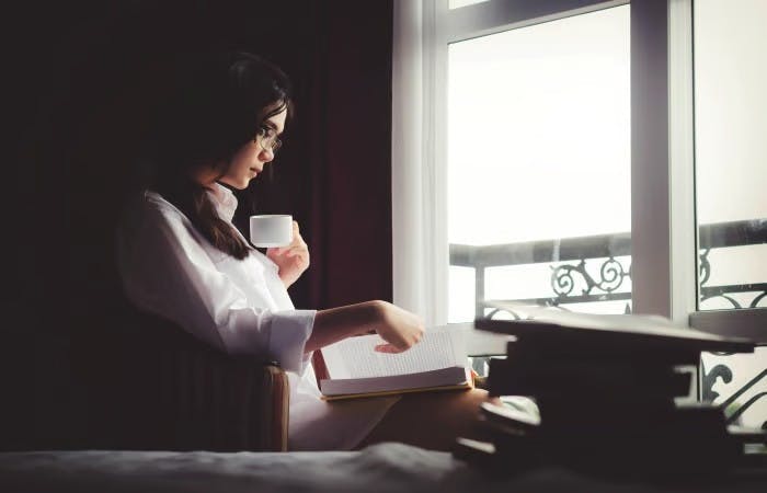 Woman sat by window reading book
