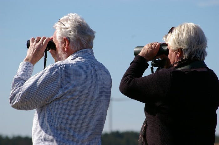 Elderly couple using binoculars to look into the distance