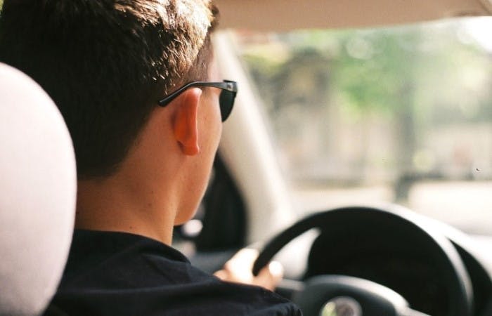 Photograph of a young man wearing sunglasses while driving