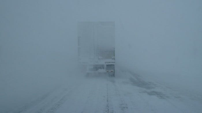 Photograph of a truck driving in heavy snow