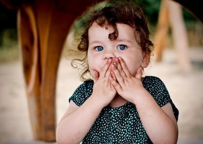 A young girl with her hands to her mouth