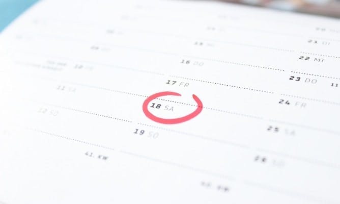 Close up of a paper calendar with a date circled in red