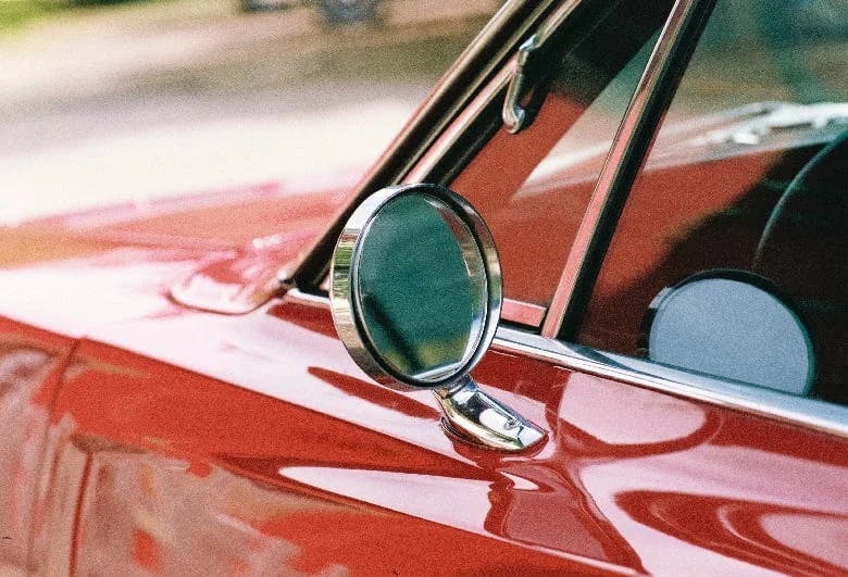 A side mirror of a vintage red car 