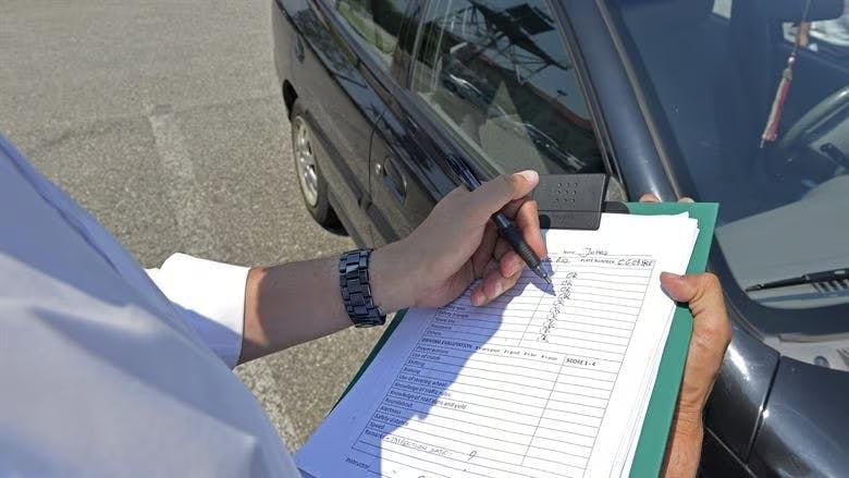 Driving examiner writing on a test mark sheet
