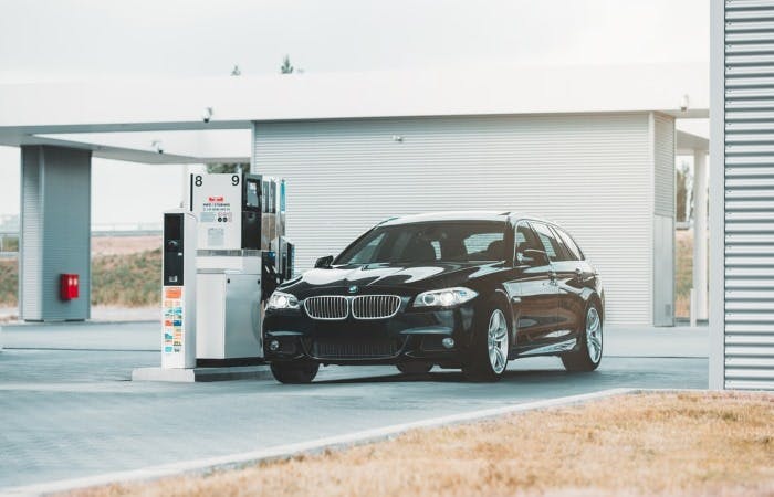 An image of a black BMW car charging at a petrol station 