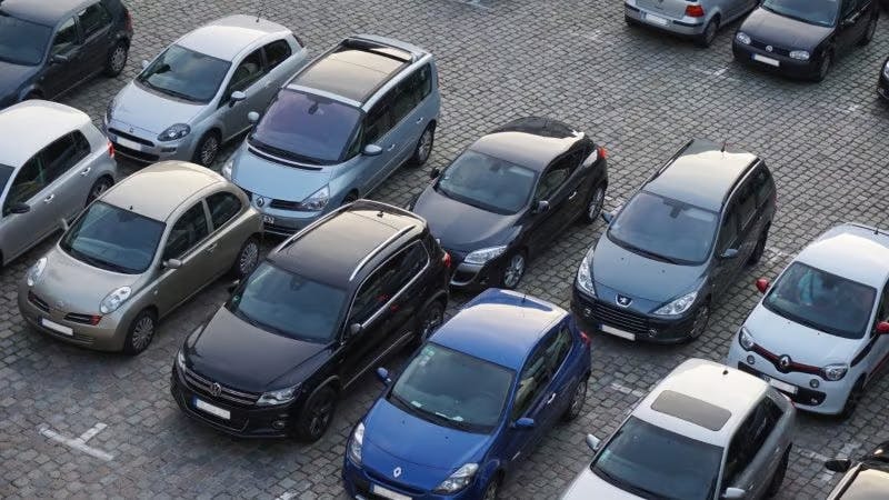 Photo of a car park with black, blue and grey cars taken from above