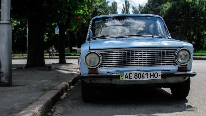 Car with Ukrainian licence plates parked next to a kerb by a park