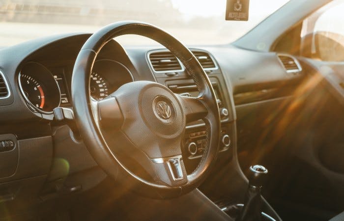 An image of the inside of a car showing the steering wheel 