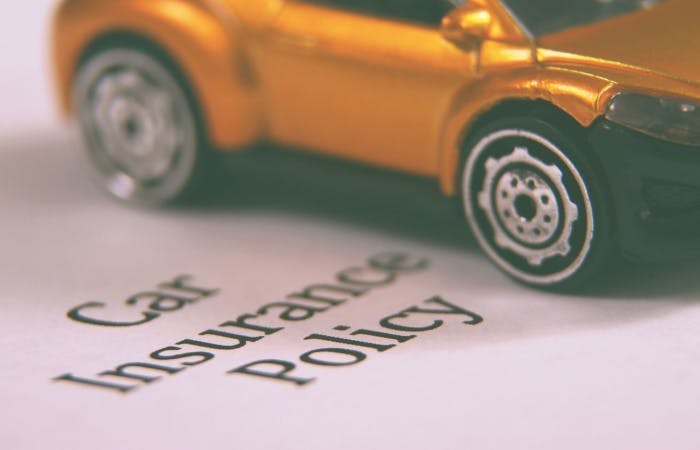Toy car on top of a piece of paper that says car insurance policy