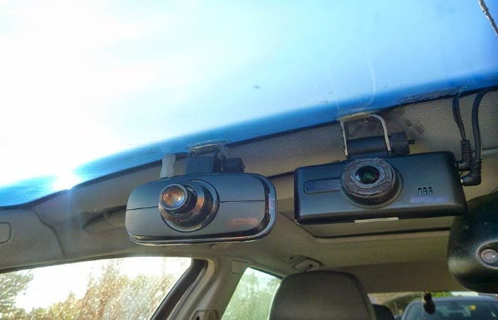 An image of two dash cameras mounted to the front of a car 
