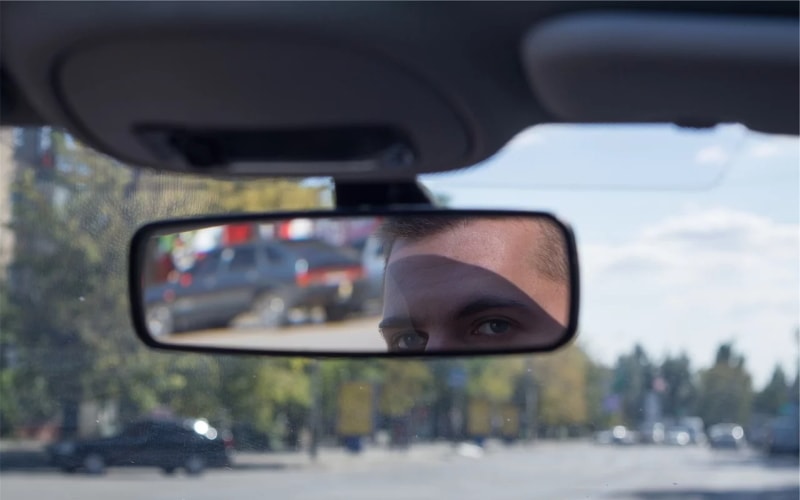 Man looking in car interior mirror