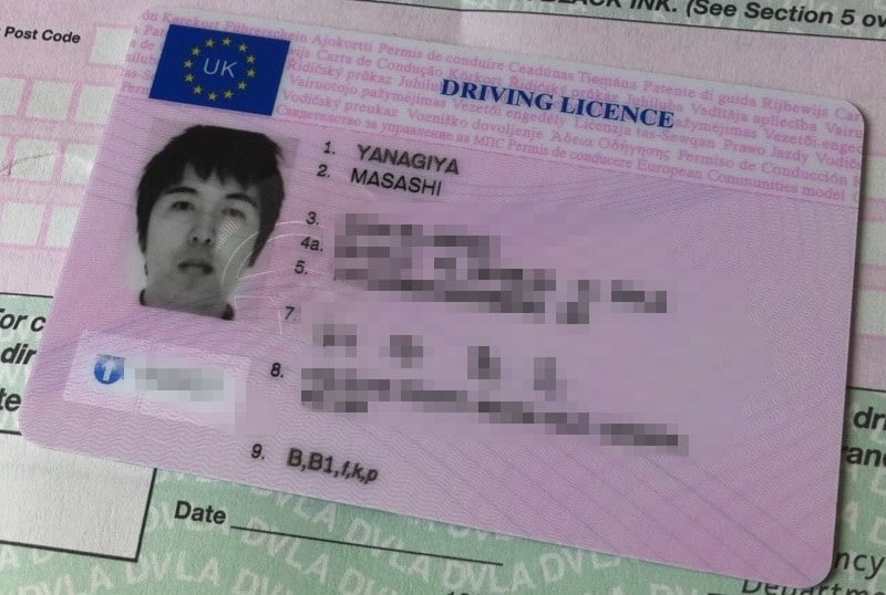 1998-style UK photocard driving licence lying on top of a paper counterpart licence