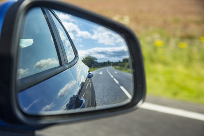 blue car side mirror reflecting the empty road
