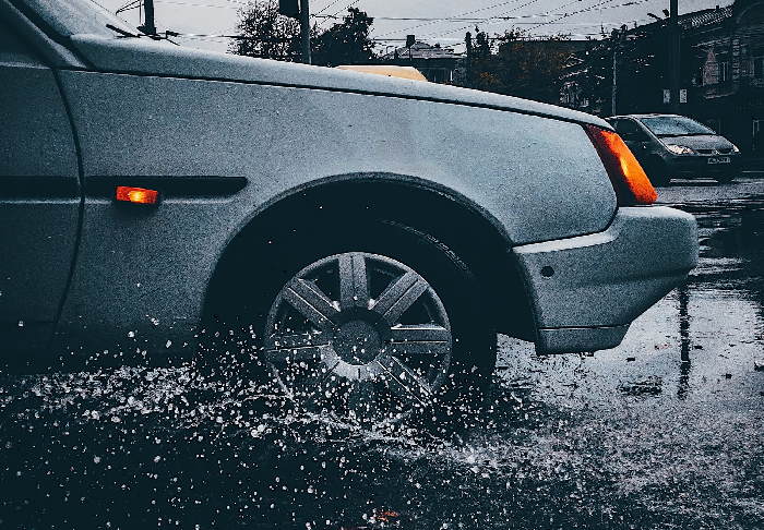 Car wheel splashing through rain puddle